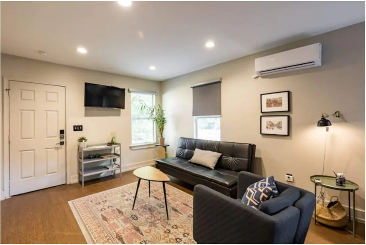 A cozy living room featuring a plush sofa paired with a wooden coffee table atop a textured rug. A potted plant adds a touch of greenery, while a piece of tasteful artwork provides a focal point on the wall. The soft lighting creates a warm, inviting ambiance, and the arrangement encourages both relaxation and social interaction.