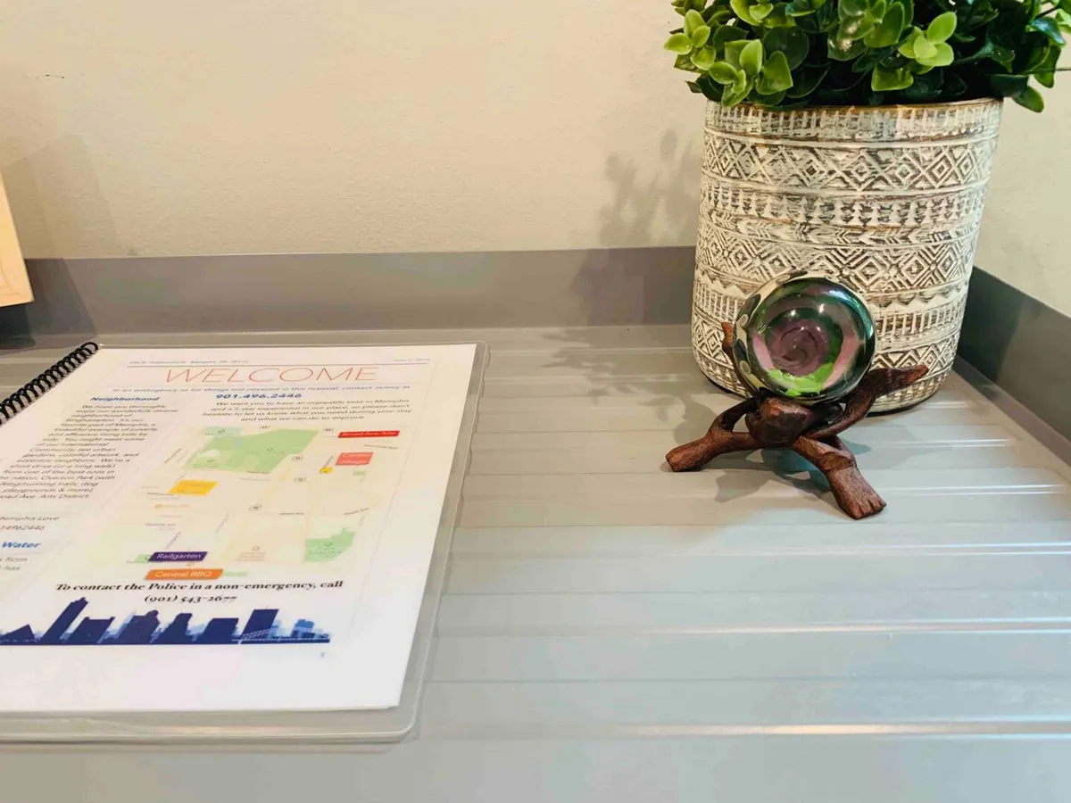 A close-up of a welcome brochure, a small potted plant, and a decorative glass piece on a table. The setting has a friendly, approachable vibe, suggesting that guests are greeted with useful information and thoughtful touches to make their stay easy and enjoyable.