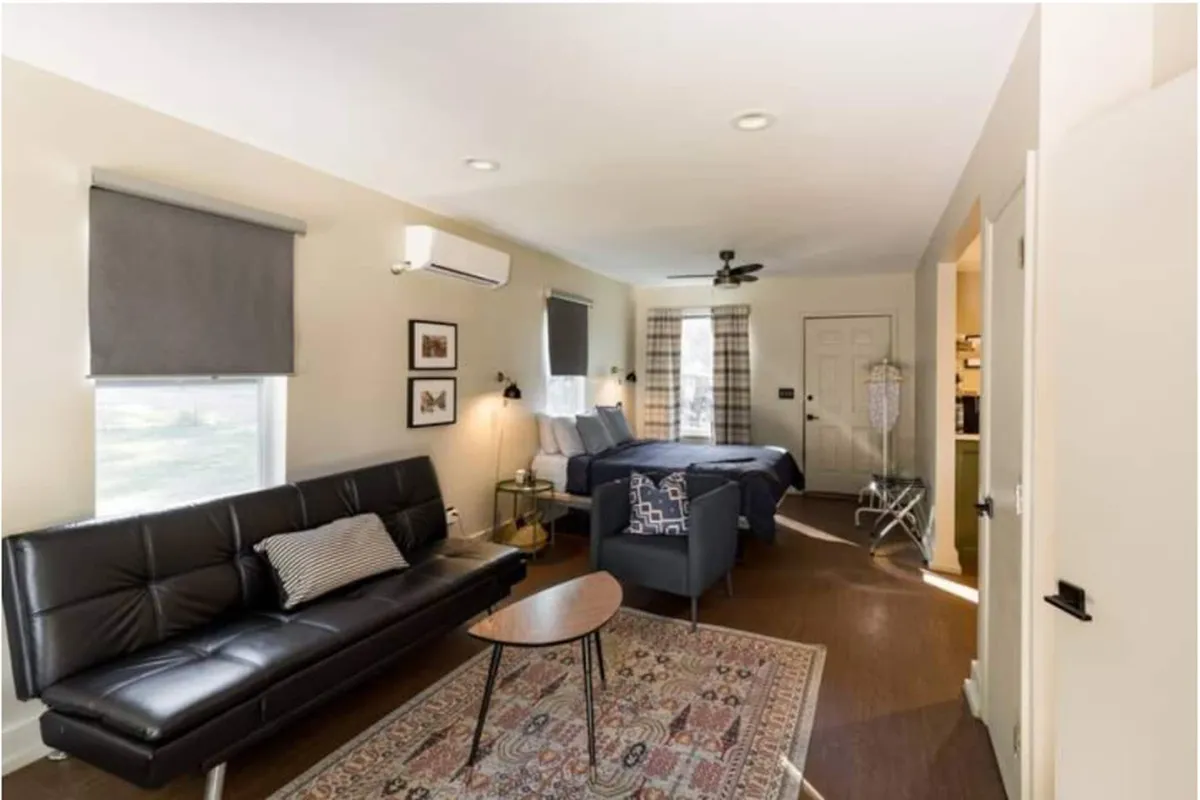 A tastefully decorated living area with a plush sofa, decorative rug, and large window providing views of the outdoors. Artwork and soft touches create an inviting, relaxed environment for couples to unwind or enjoy a quiet morning.
